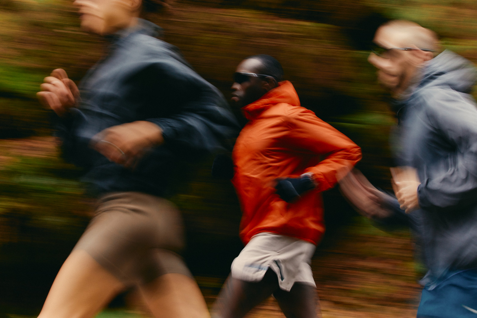 A group of runners moving together along a wooded trail