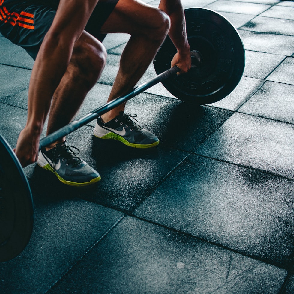 Athlete setting up a deadlift on a dark gym floor